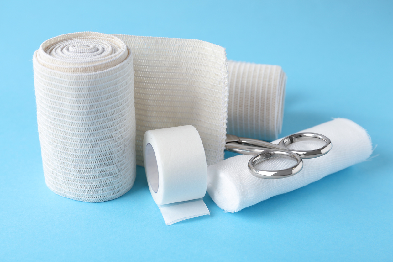 medical-bandage-rolls-sticking-plaster-and-scissors-on-light-blue-background