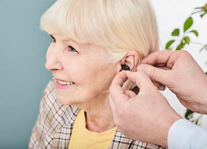 audiologist-inserting-intra-ear-hearing-aid-to-senior-woman-patient-close-up-hearing-solution-for-elderly-people